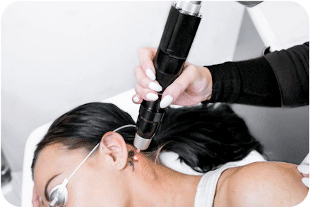 laser being used to remove a neck tattoo on a woman lying down